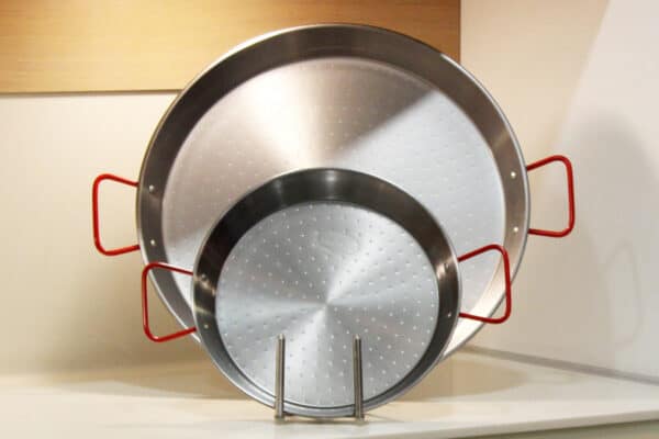 Magefesa two carbon steel paella pans with red handles in the kitchen