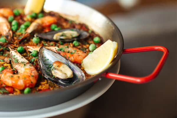 Magefesa carbon steel paella pan with rice, shrimps, mussels and lemon